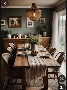 a dining room table with plates and place settings on it, in front of a window