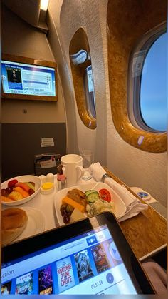 an airplane meal is being served on the tray with a digital tablet next to it