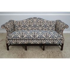 a blue and white patterned couch sitting on top of a carpeted floor next to a wall