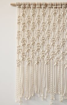 a white wall hanging with ropes and chains