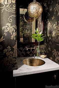 a bathroom sink sitting under a mirror next to a vase with a plant in it