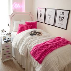 a bed with pink and white comforters in a bedroom next to two pictures on the wall