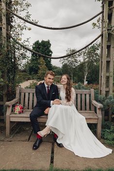 a bride and groom sitting on a wooden bench