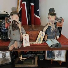 two wooden dolls sitting on top of a table next to an old camera and flag