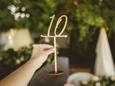 a person holding up a wooden table number with the number ten on it's side