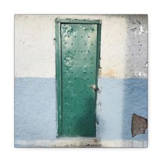 an old green door on the side of a white and blue building with holes in it