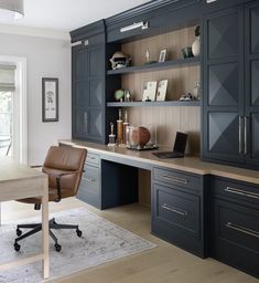 a home office with dark blue cabinets and leather chair