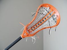 an orange and white lacrosse goalie hitting a ball with it's head in the air