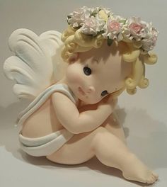 a little angel figurine sitting on the ground with flowers in it's hair