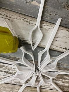 white plastic utensils hanging from the ceiling in front of a wooden wall with peeling paint