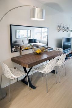 a dining room table with white chairs and a large mirror on the wall above it