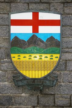 a brick wall with a coat of arms on it and mountains in the back ground