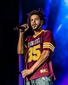 a man with dreadlocks standing on stage holding a microphone in front of him