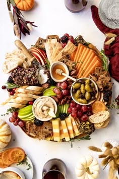 an assortment of cheeses, crackers and grapes on a platter