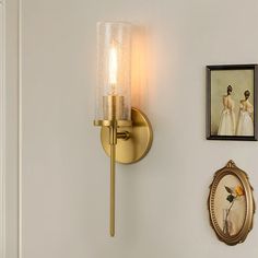 the wall light is next to two pictures on the wall