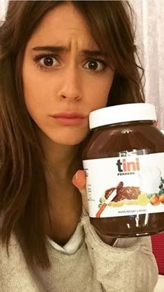 a woman holding a jar of nutella in front of her face and looking at the camera