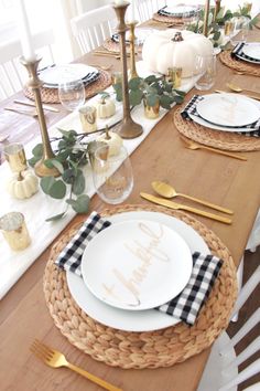 the table is set with plates, silverware and gold place settings for thanksgiving dinner