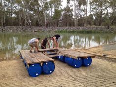 two men are working on some kind of wooden structure by the water's edge