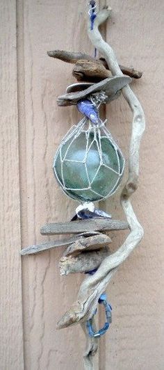 a piece of driftwood hanging on the side of a building with sea glass in it