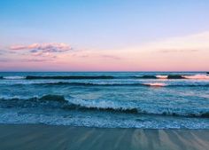 the ocean waves are rolling in and out on the beach at sunset or sunrise time