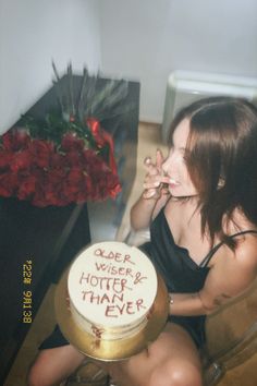 a woman sitting in front of a cake with writing on it