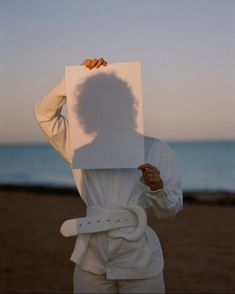 a person holding up a white piece of paper with the shadow of a woman's head