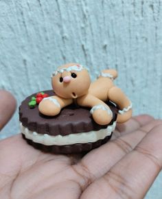 a small teddy bear sitting on top of a piece of cake in someone's hand