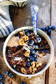 a bowl filled with cereal and blueberries on top of a wooden table