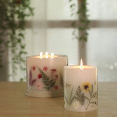 two white candles sitting on top of a wooden table