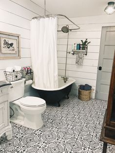 a bathroom with a black and white bathtub next to a toilet under a shower curtain