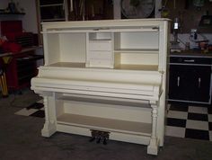 a white piano sitting in the middle of a room with black and white checkered flooring