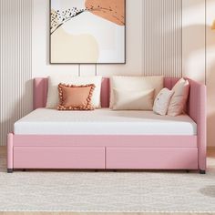 a pink daybed with pillows on it in front of a wall mounted art piece