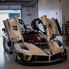 a white and blue sports car parked in a garage with its door open to the side