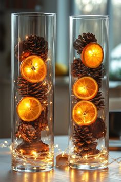 two glass vases filled with orange slices and pine cones