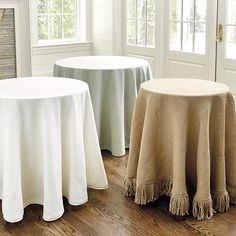 two round tables with tassels on them in front of a fireplace and windows