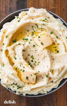 mashed potatoes topped with butter and parsley in a bowl on a wooden table