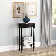 a blue vase sitting on top of a wooden table next to a lamp and pictures