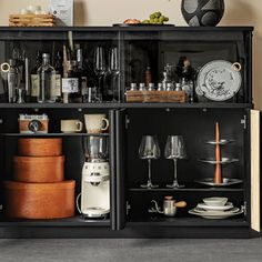 an open cabinet filled with lots of wine glasses and other items on top of it