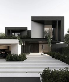 a car is parked in front of a modern house with black and white exteriors