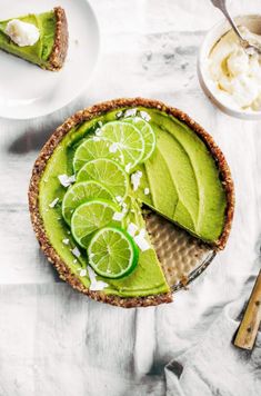 a pie with limes and whipped cream on top is sitting on a white table