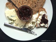 a white plate topped with bread and cheese covered in jam next to crackers on a table