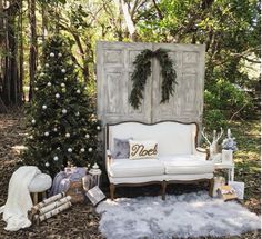 a white couch sitting next to a christmas tree in the middle of a forest filled with trees