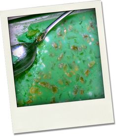 a spoon sitting in a green liquid filled bowl