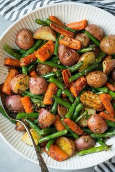 a white bowl filled with potatoes and green beans on top of a striped table cloth