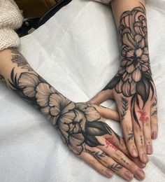 two hands that have tattoos on them and flowers on their palms, both with red ink