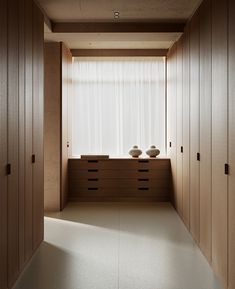 an empty room with two vases on the counter and wooden cabinets in front of it