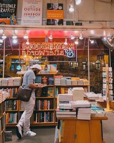 a man standing in front of a book store with lots of books on the shelves