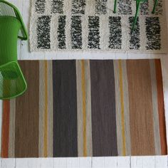 a green chair sitting on top of a rug next to a wooden table and chairs