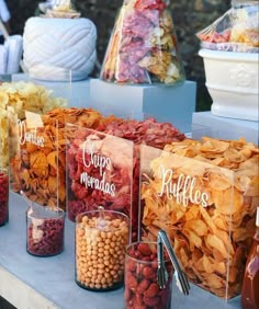 many different types of snacks on display in glass containers with name tags attached to them