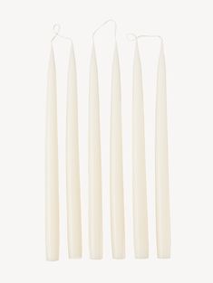 four white candles are lined up in a row